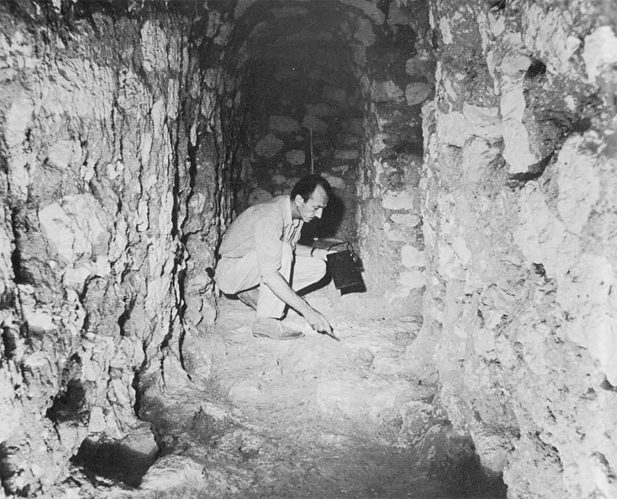 A man carefully cleaning a temple tunnel floor.