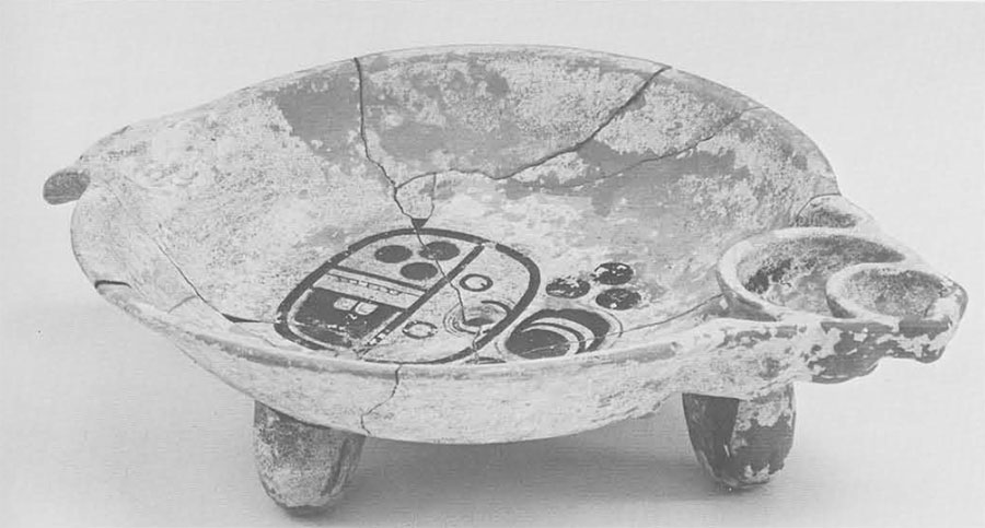 A shallow bowl with legs, a design painted in the middle.