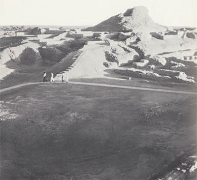Four people walking to the stairs that lead to the Stupa in the distance.
