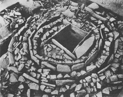 Stone cist with concentric circles of rocks surrounding it.