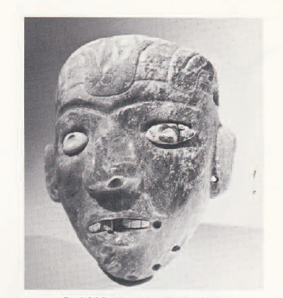 A stone burial maskette, teeth bared.