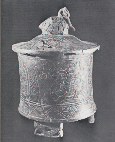 Cylindrical, lidded vessel with bird handle and legs, bird designs incised into the vessel.