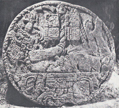 Round stone altar with a serpent-human figure carved into it.