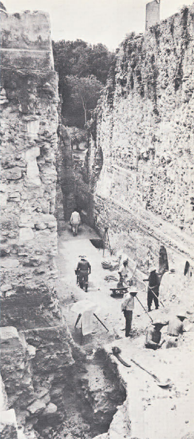A group of people excavating in a deep pit.