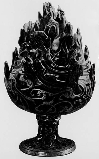 Bronze incense burner, Po-shan-lu, found in the recess (bathroom) of the coffin chamber in Liu Shêng's tomb. Incense burners of this type, made either of bronze or pottery, are one of the most common utensils placed in tombs during the Han period. They represent a cosmic mountain; on this one as on most of them a legendary hunter is shown and various animals. However, in beauty and quality of workmanship this one is unsurpassed. It is inlaid with gold, its foot is made of winding dragons in openwork, the bowl is decorated with elegant cloud patterns and the tops of mountains accentuated by gold and filigree work. When incense was burnt in it, the smoke rose through perforations giving the impression of mist drifting over the mountain side. Western Han 2nd century B.C. Height, 25.6 cm. Kaogu 1972. No. 1 Pl. 4. 