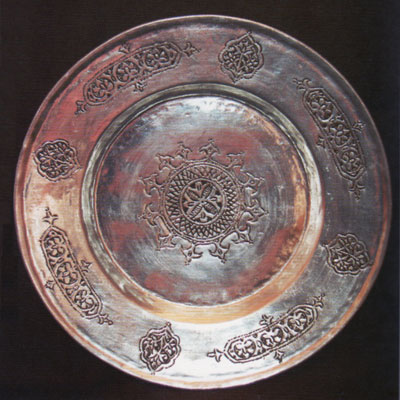 A bronze plate with scrolling decoration.