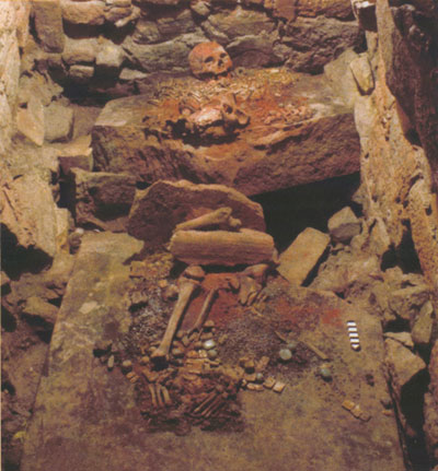 Tomb with human remains lying on a broken slab.