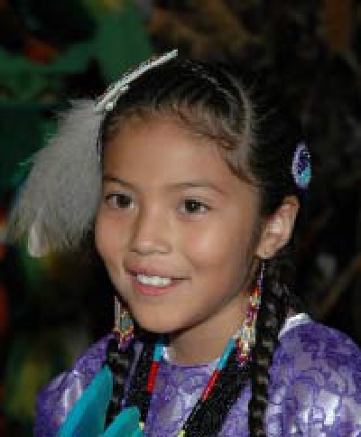 A young girl with her hair in braids, a feather attached to her hair.
