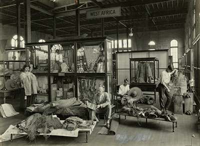 Curator Charles R. Toothaker and staff at the Philadelphia Commercial Museum prepare objects for the West Africa display, 1921. Many of the objects in this photo, including the robe in the back and the hats on the left, are now part of the Penn Museum collection. Photo courtesy of PhillyHistory.org, a project of the Philadelphia Department of Records.