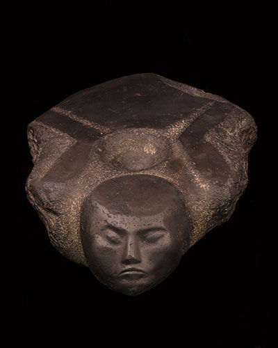A stone temple door socket in the shape of a prisoner lying on his stomach with his arms bound behind him.