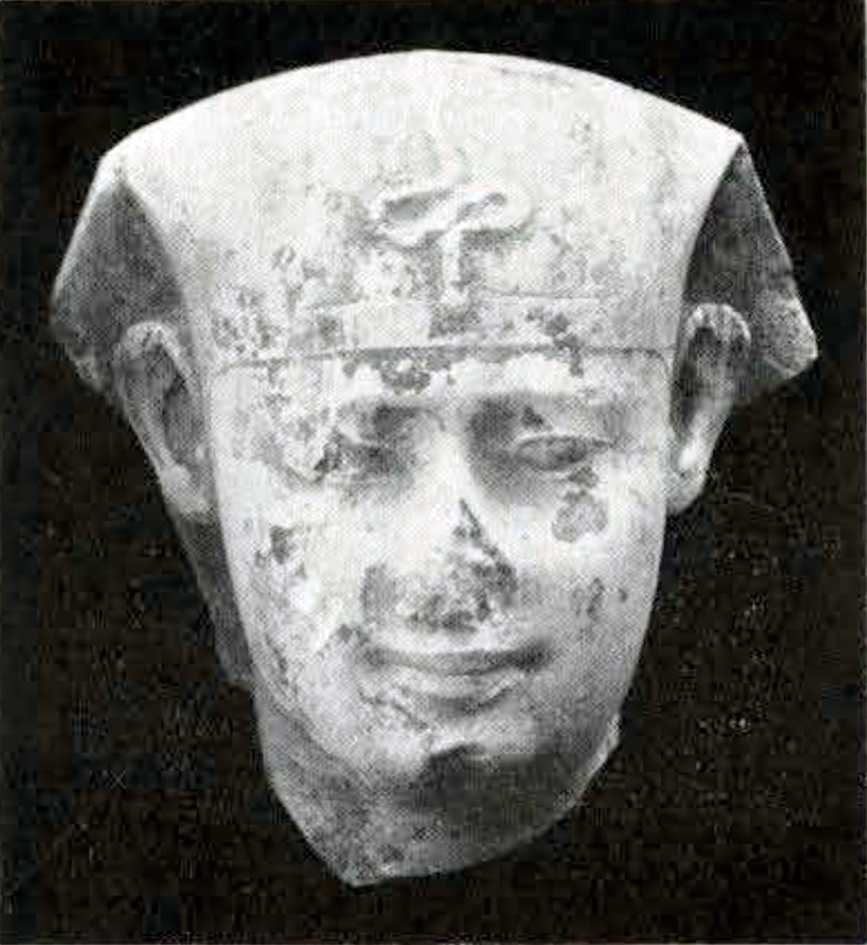 Head of a stone statue with nose missing, wearing headpiece