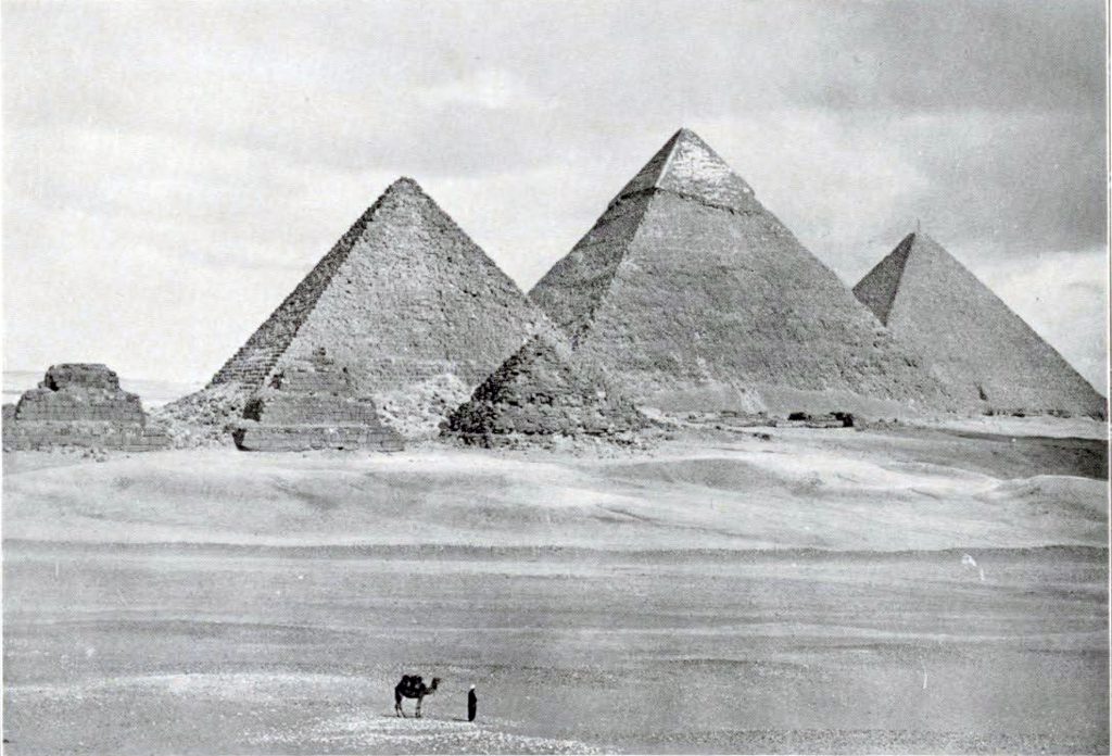 The pyramids at Giza and the surrounding dessert with a man and his camel in the foreground