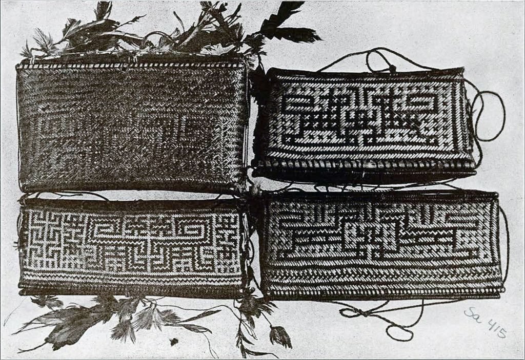 A set of four small baskets with similar but subtly different designs, the two on the left have feathers