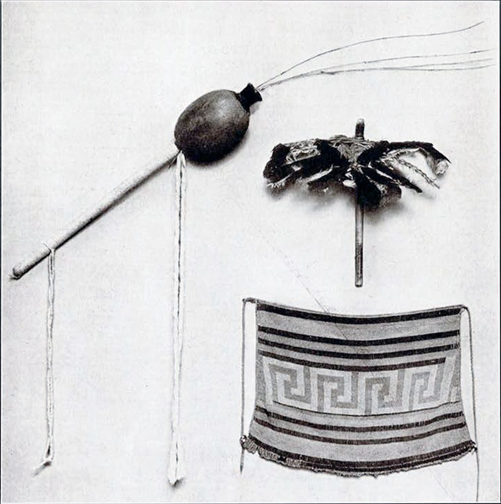 A gourd rattle, a bird figure made of feathers, and a beaded apron