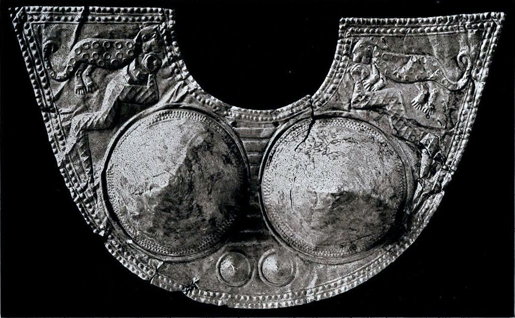 A half circle gold breastplate with jaguar and anaconda imagery