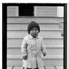 A-gux-daet. Child in Victorian winter dress on porch. Haines, Alaska. 1917