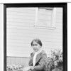 Sxan-du-n-la. Standing outside, along side of house, among flowers, summer 1918. Haines, Alaska.
