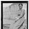 Nukt yi-la. Athabascan woman sitting by snow fence. 