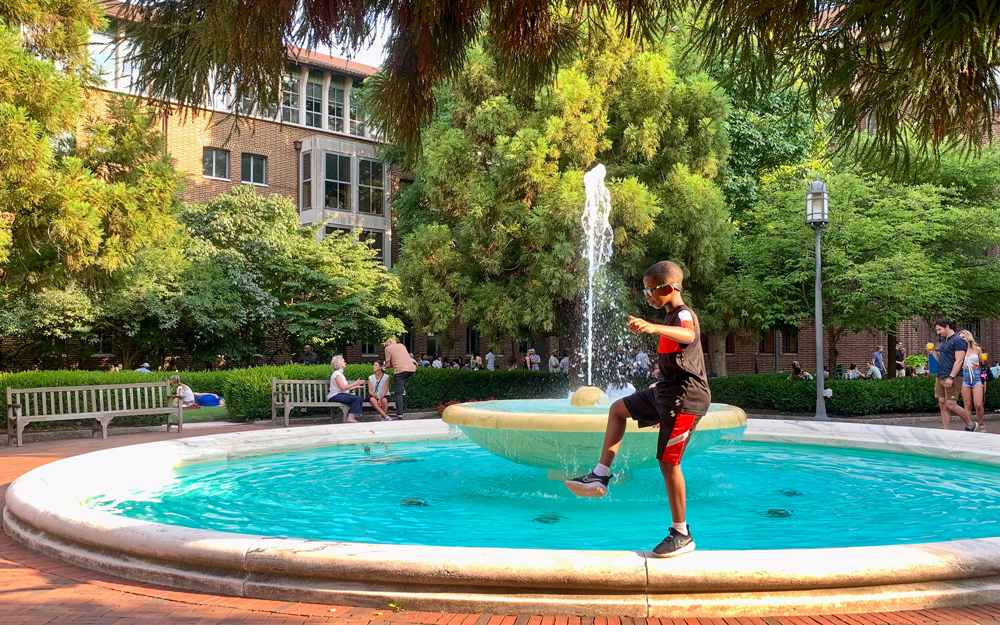 A child enjoying a fountain in the gardens.
