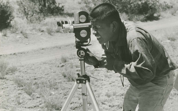A person filming in the field.