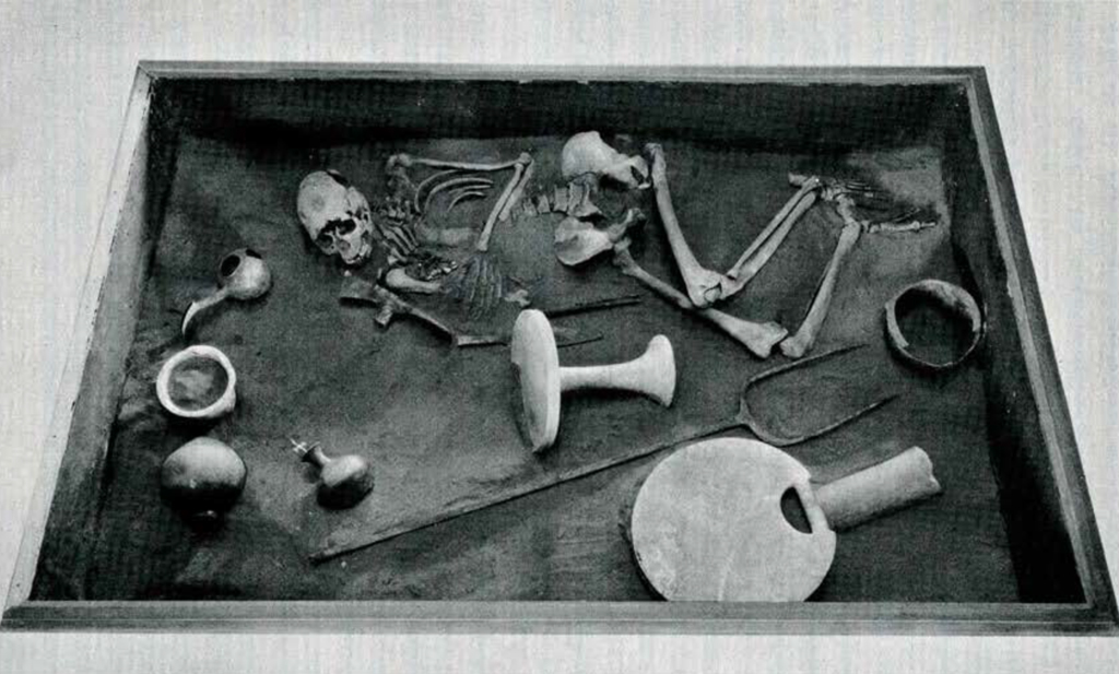 Reconstruction of a burial with remains and many objects scattered about
