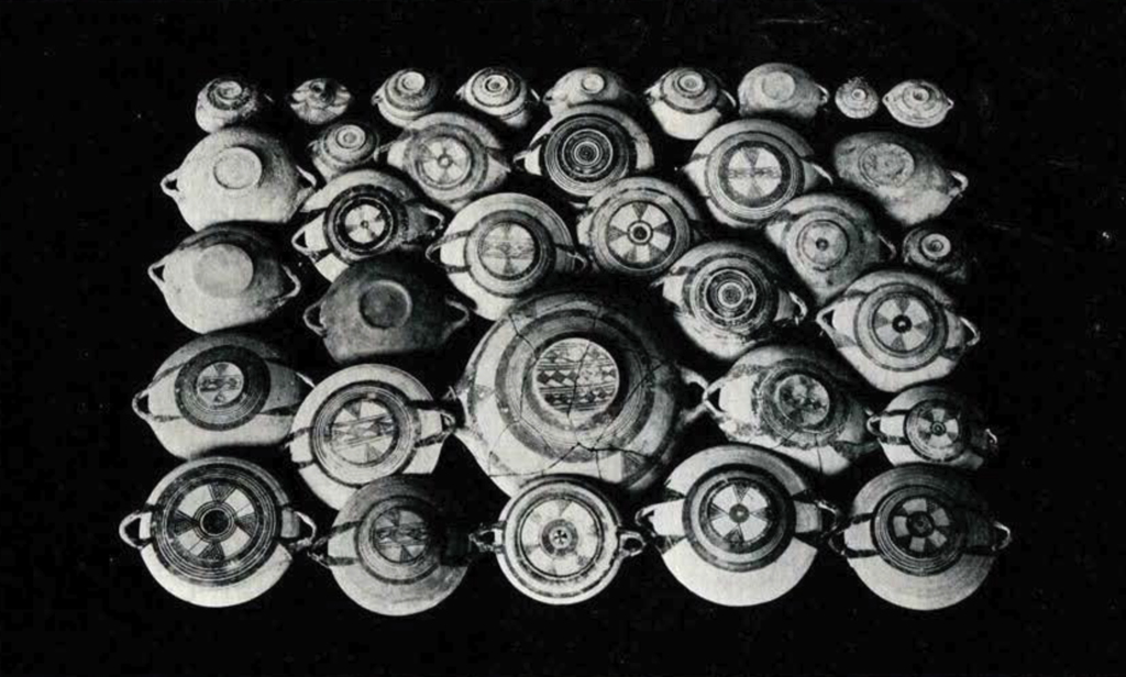 Plates with handles, facing down to show their designs, arranged in a grid