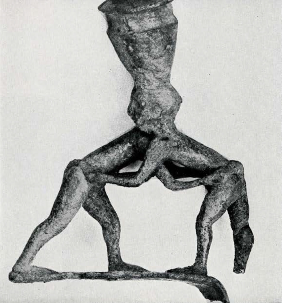 Bronze statue of two Wrestlers, each with a pot on his head, the men stand in a crouching position grasping each other's belt.