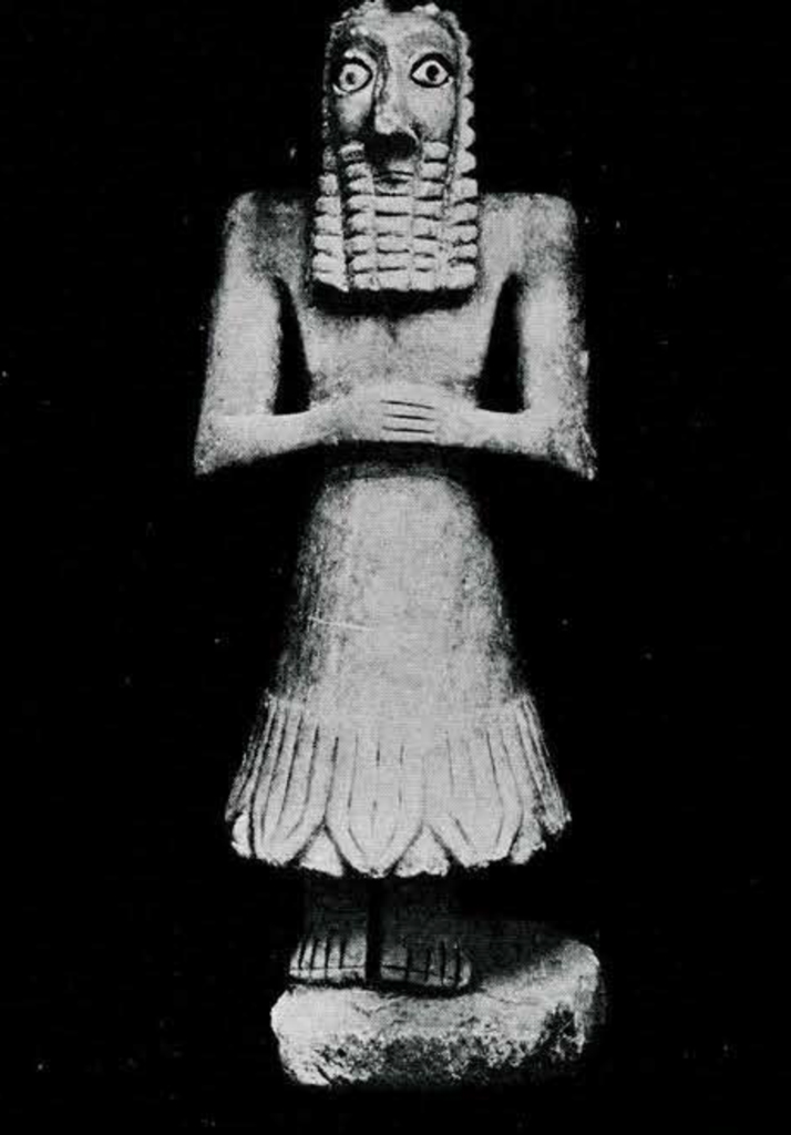 Human statuette with long hair and beard, and hands clasped at the waist