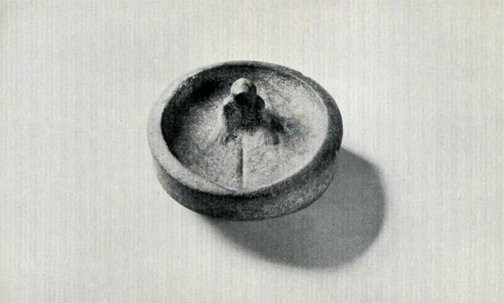 Shallow stone lamp bowl with a seated figure in the middle