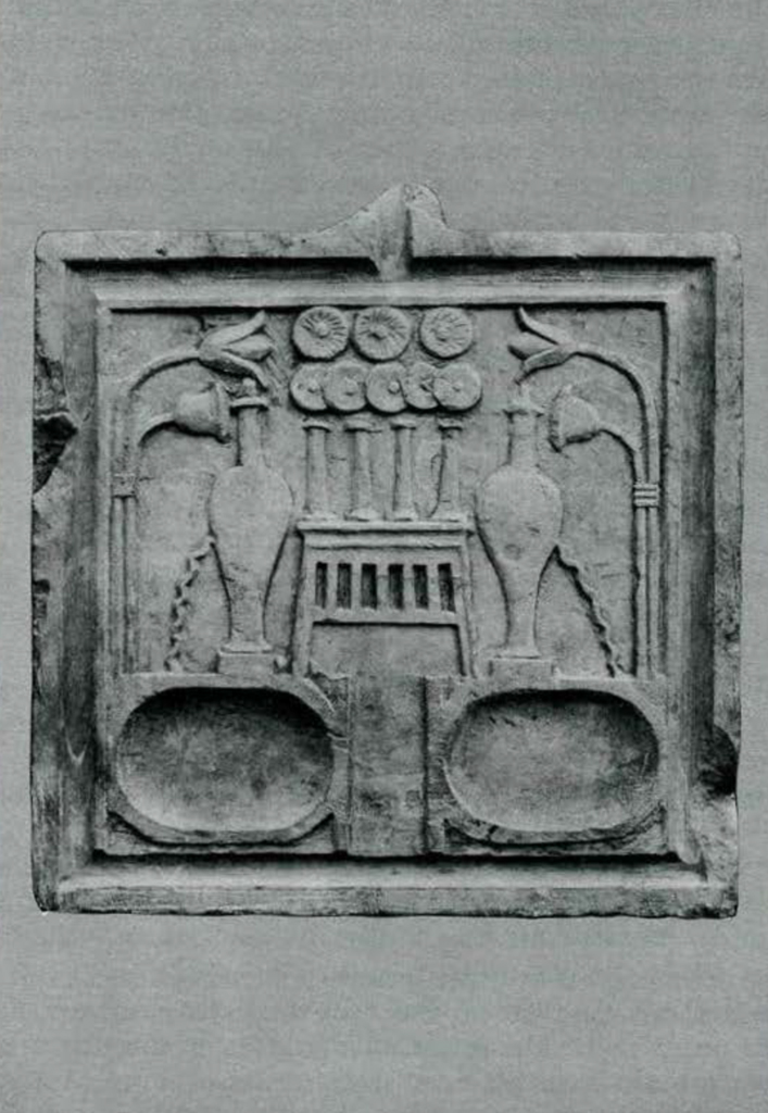 Carved stone offering table with symmetrical design showing bowls, flowers, and offerings