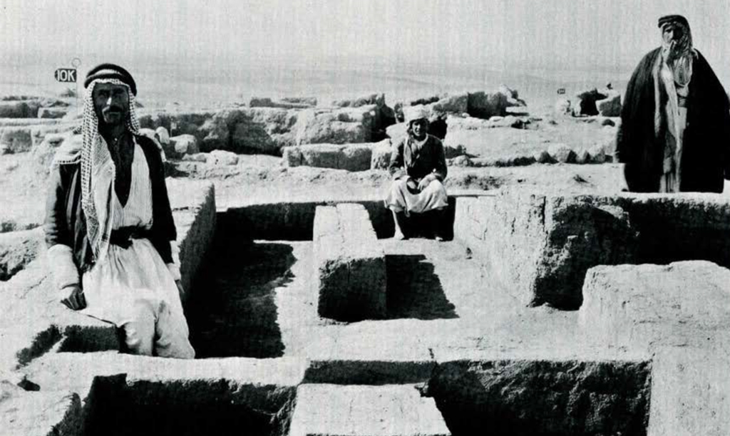 Three men standing in a partially excavated temple stratum