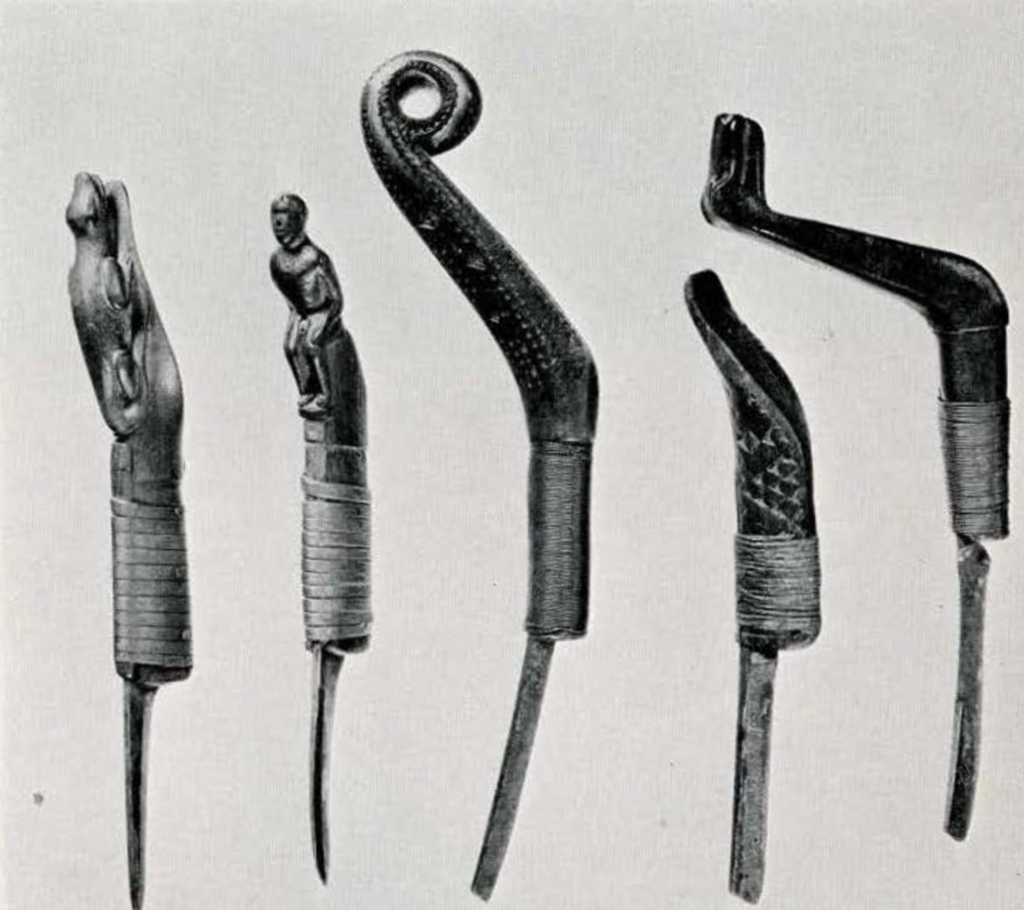 Five crooked knives with wooden handles all carved into different figures, including a seated person and a lizard