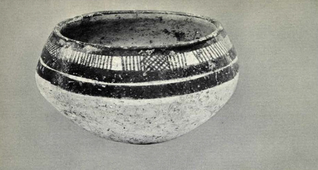A shallow bowl painted with horizontal stripes and cross hatching on the top half