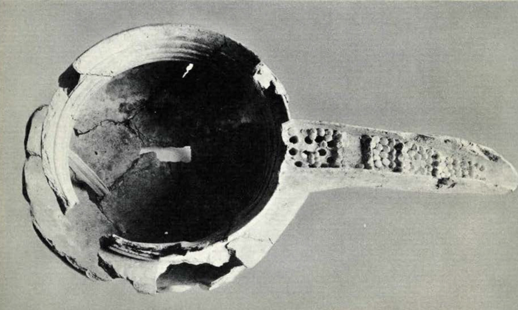 A fragmented bowl with a spout decorated with a pebble texture