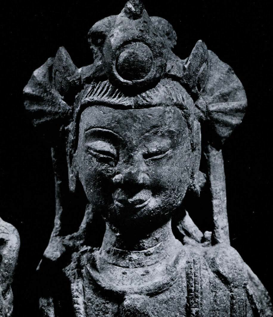 Close up, shoulders up view of a Bodhisattva statue with sacred pearl is center of headdress with elaborate scarves and drapery