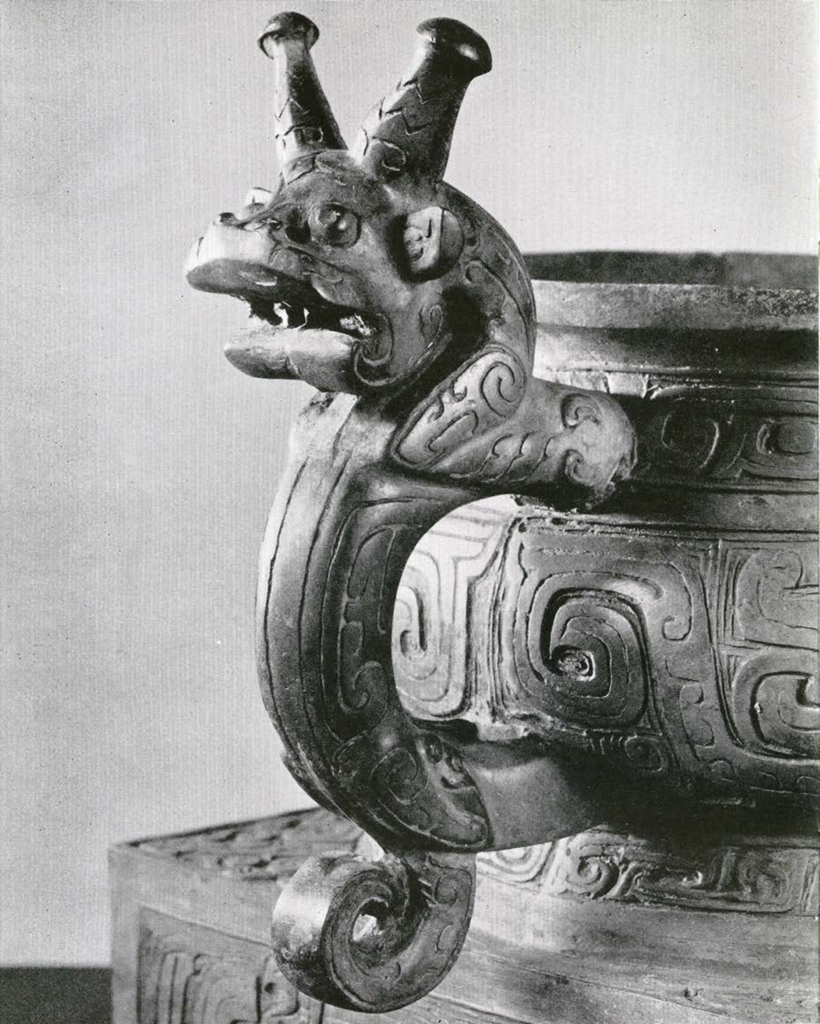 Close up of a bronze handle in the shape of a beast's head with two antlers or antenae