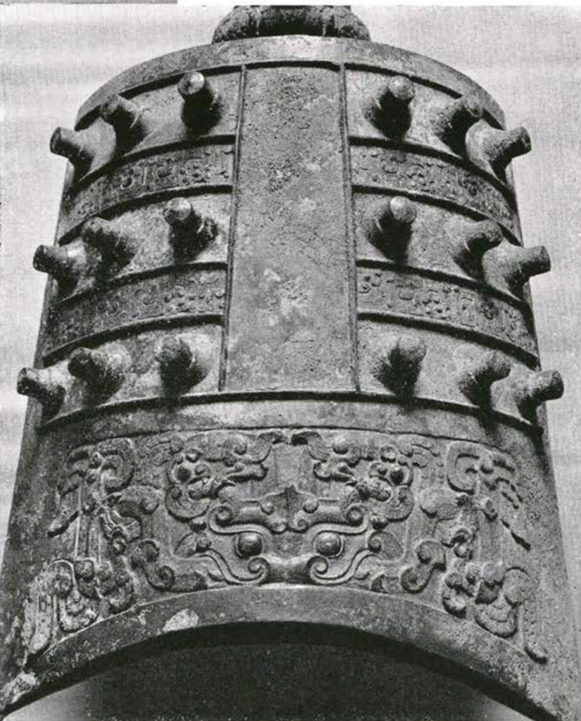 Close up of bronze bell body showing studs and register of decor at the bottom