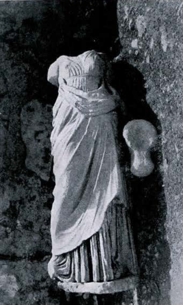 A headless and armless statue of a woman in draped sheetwear
