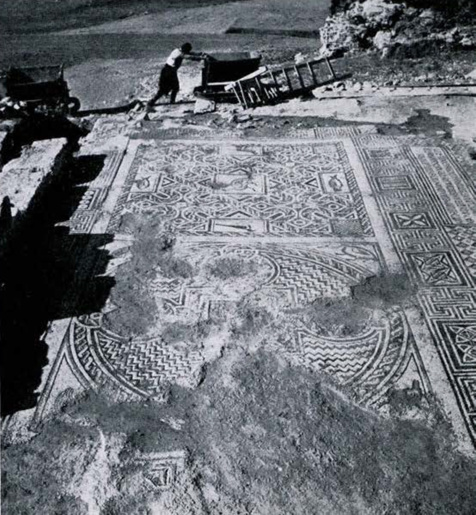View of an excavated mosaic, a man pushing a cart in the background