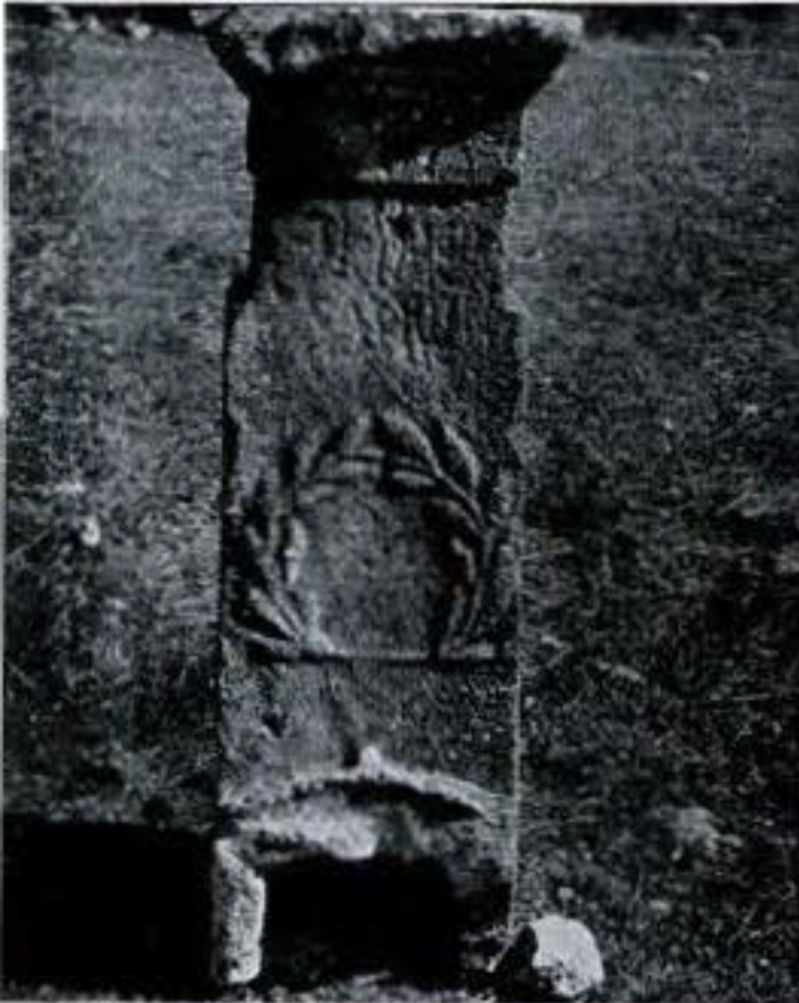 A stone column with an inscription and a laurel carved in it