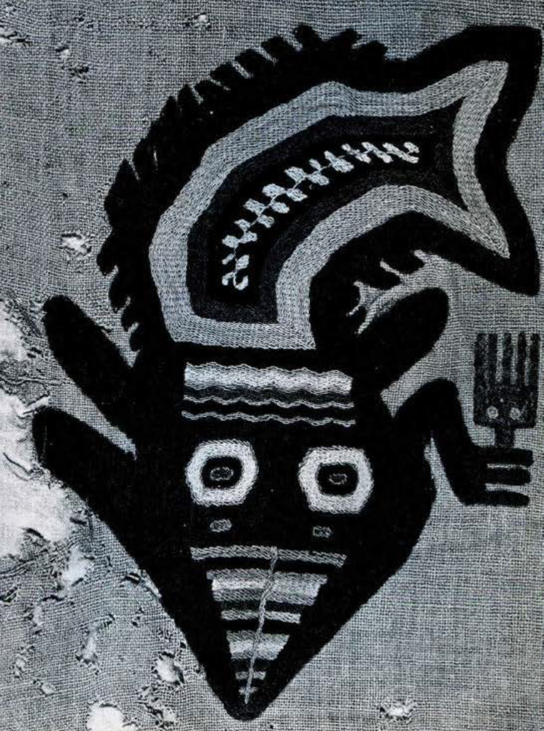 Close up of a stylized orca embroidered on cloth, holding a fork or comb