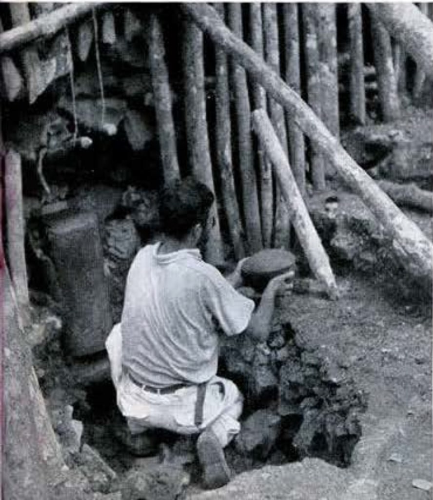 A man removing a bowl from beneath a structure of wood and stone