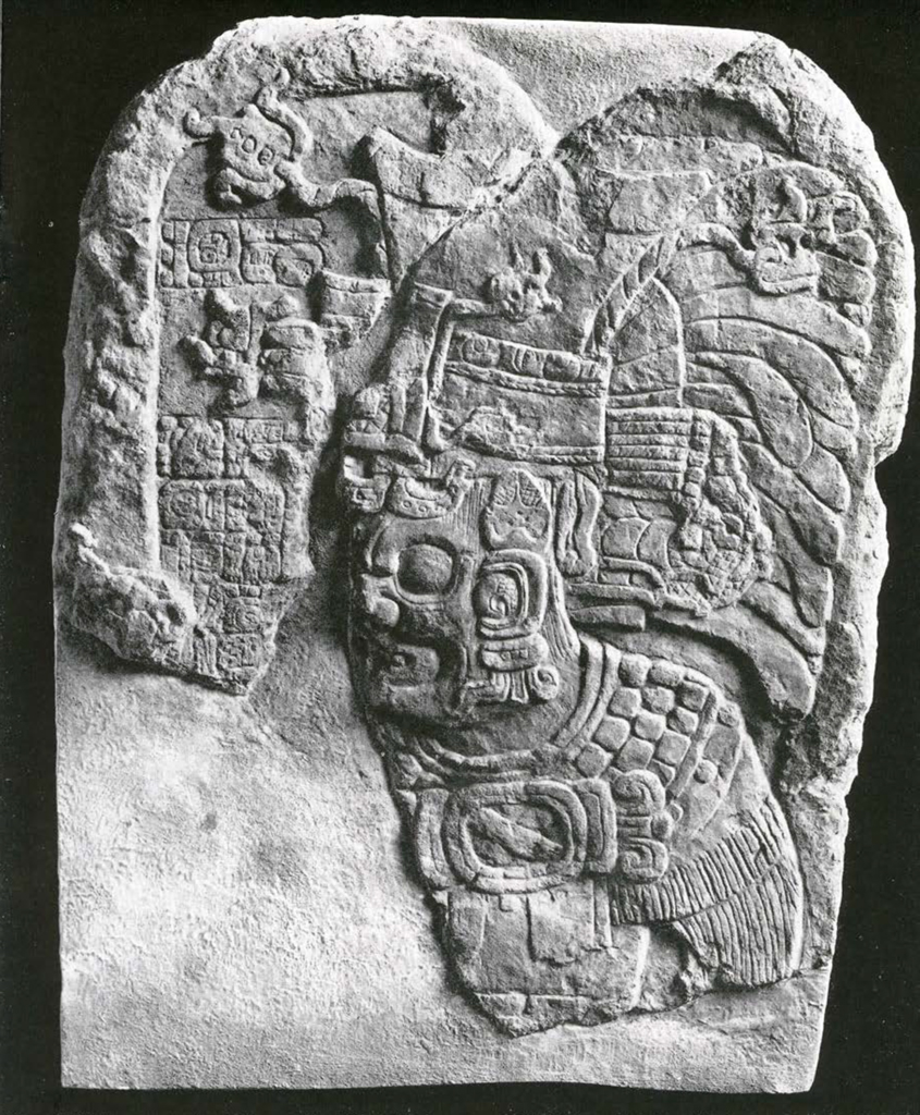 Stone fragment of a stela showing a man with a grotesque face or mask and headdress