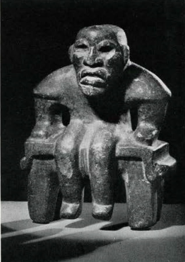 Carved stone figure of a person seated on a bench or throne with their arms bent to their sides and hands resting on the bench