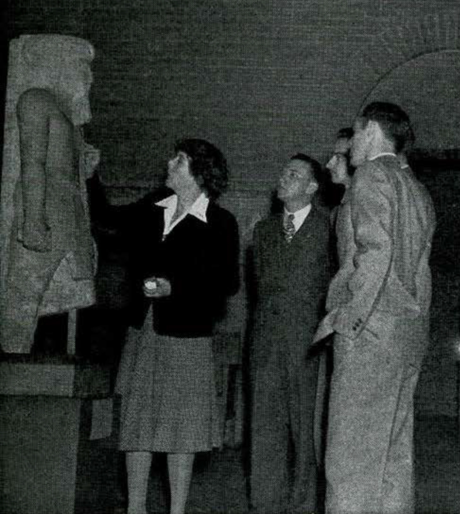 A small group of professionals gathered around an Egyptian statue