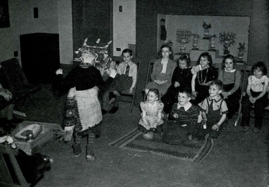 A group of seated school children watching a Hopi danced performance