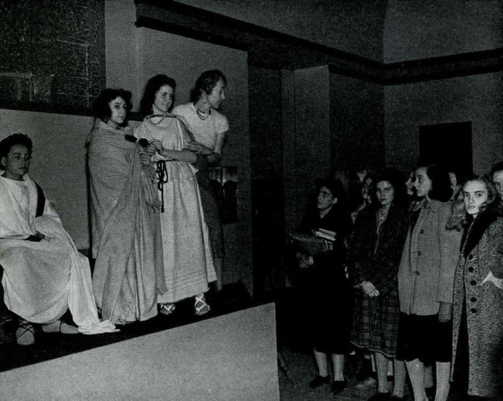 A group of students viewing a group of people dressed in ancient Greek and Roman garb