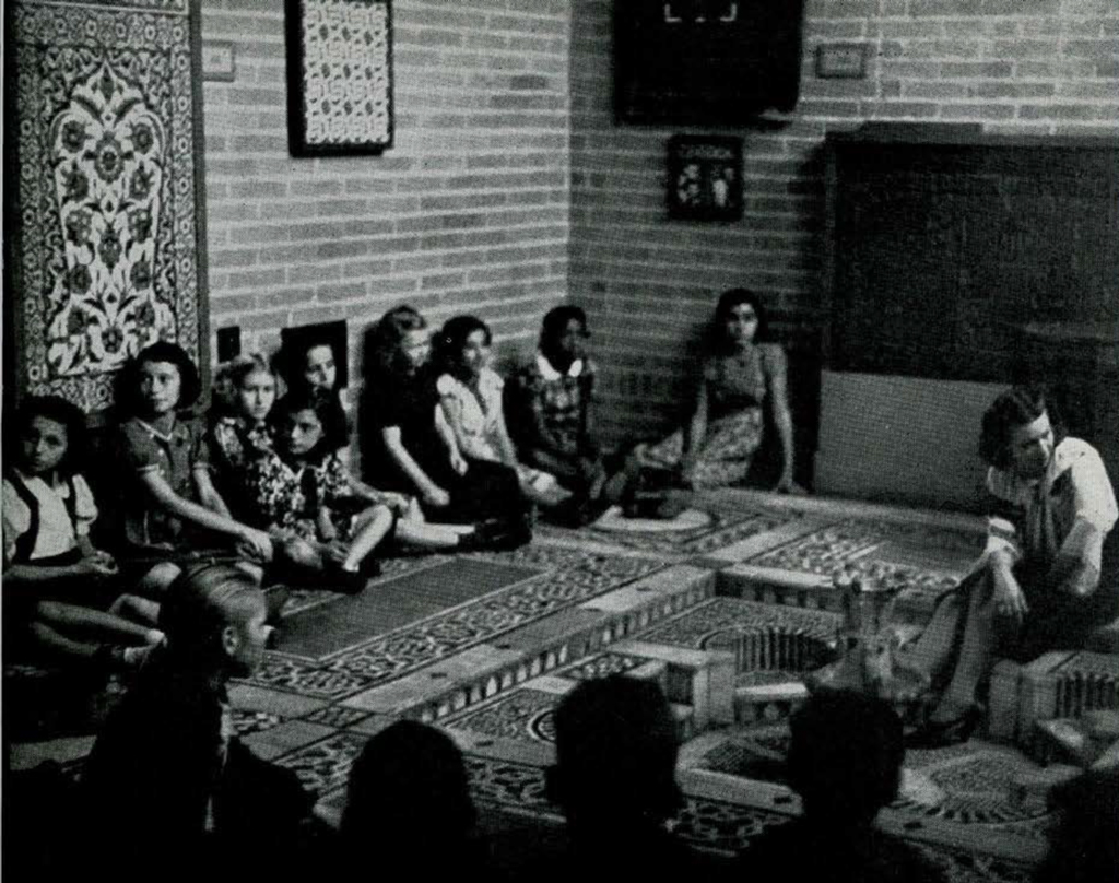 A group of school children seated on the floor around a mosaic floor display