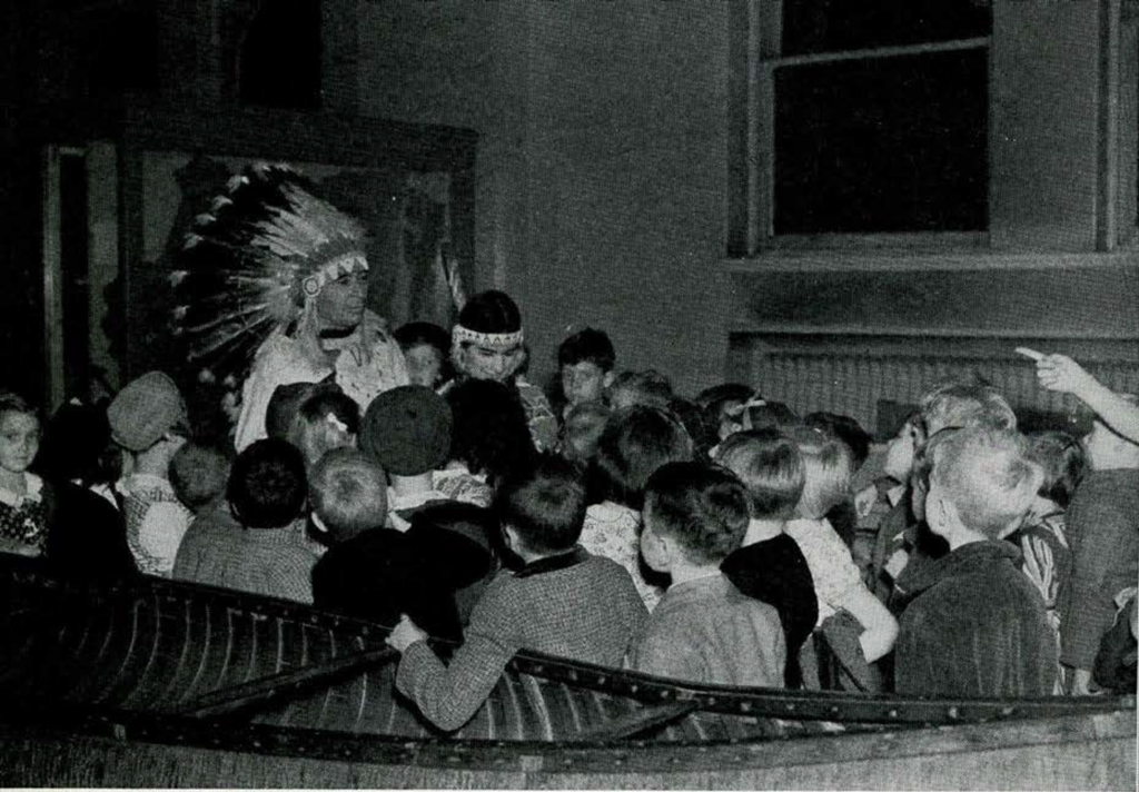A group of school children listening to a Native American couple