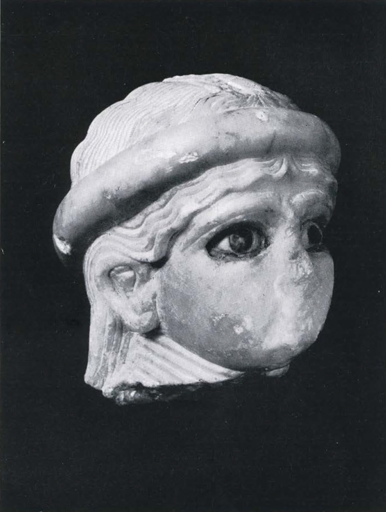 Female head, alabaster, broken off at the neck; nose and lower part of face damaged; the eyes inlaid, wavy head